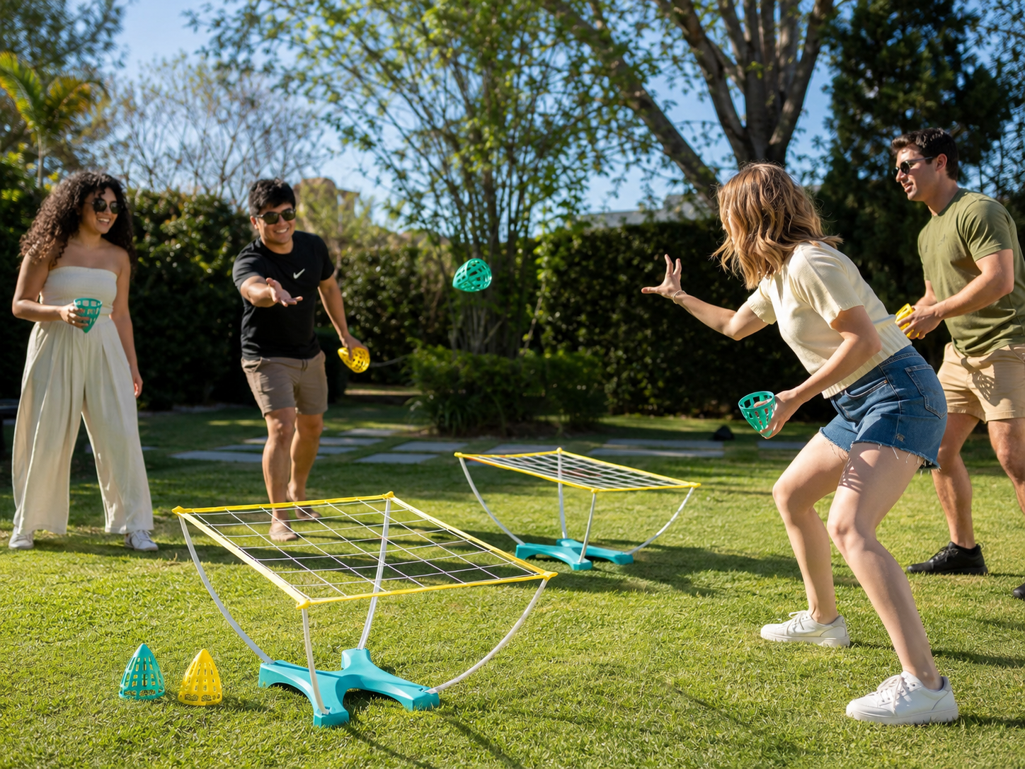 Friends playing Cone Toss outdoors with teal and yellow toss cones and two net targets set up on a sunny backyard lawn.